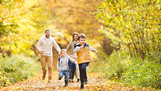 Vader moeder en twee kinderen rennen in het herfstbos